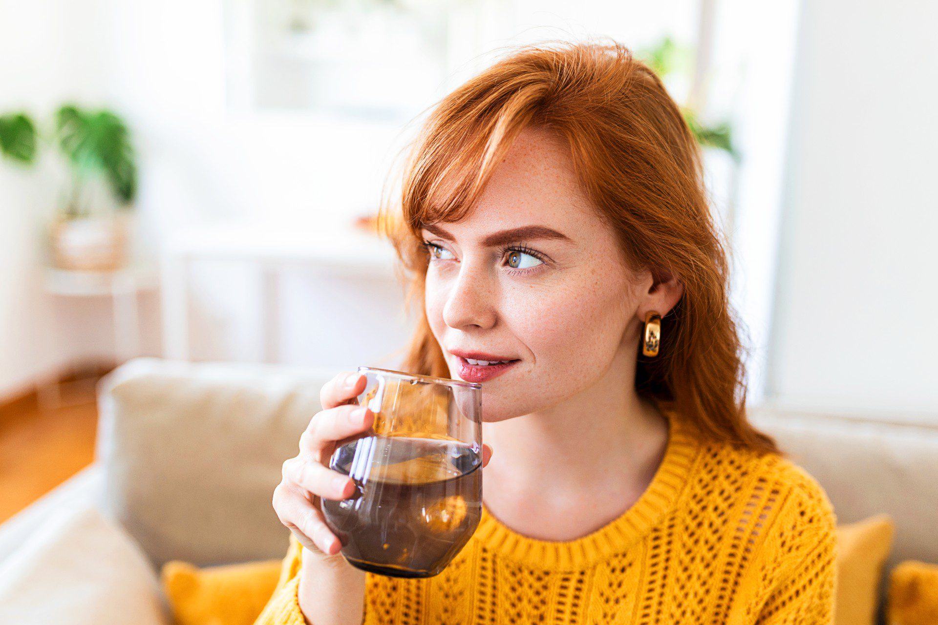 Drinking water. Happy young woman smiling while holding a glass of water